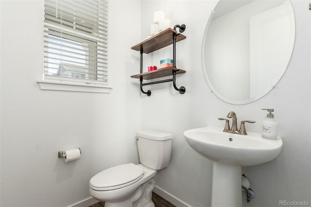 half bath with a sink, baseboards, and toilet