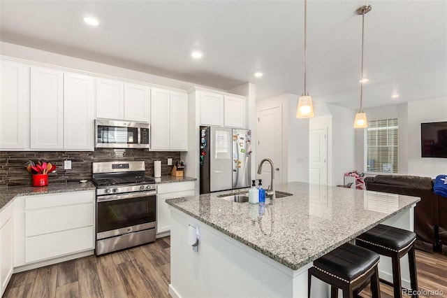 kitchen featuring a sink, stainless steel appliances, dark wood finished floors, and decorative backsplash