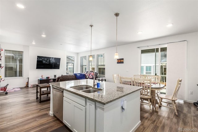 kitchen featuring light stone countertops, an island with sink, dark wood-style flooring, a sink, and stainless steel dishwasher