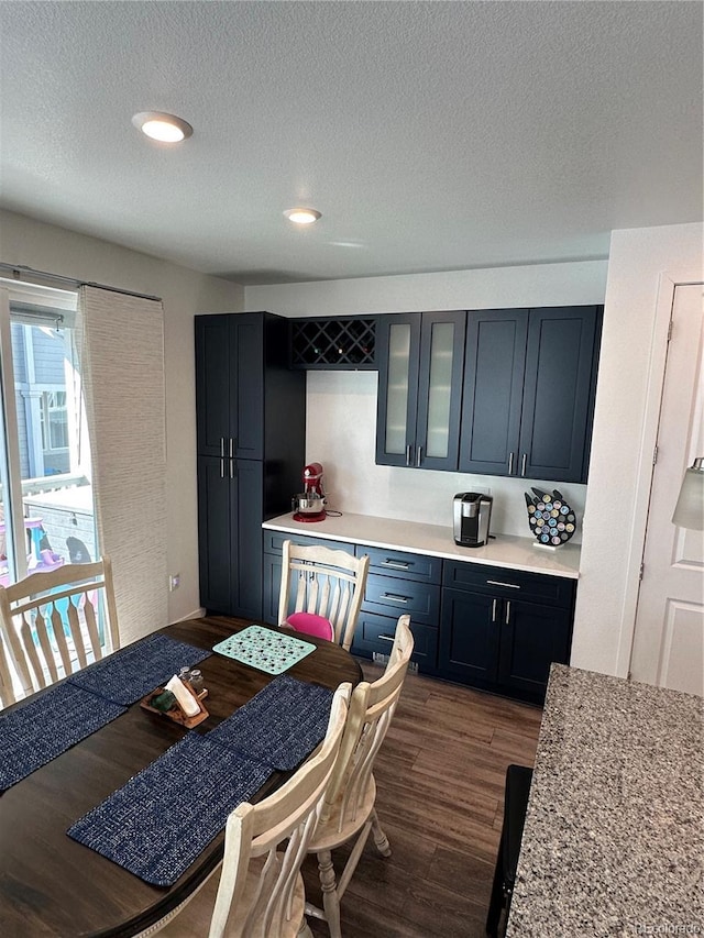 kitchen featuring dark wood finished floors, light countertops, glass insert cabinets, and a textured ceiling