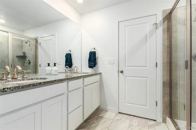 full bathroom with double vanity, a stall shower, marble finish floor, and a sink