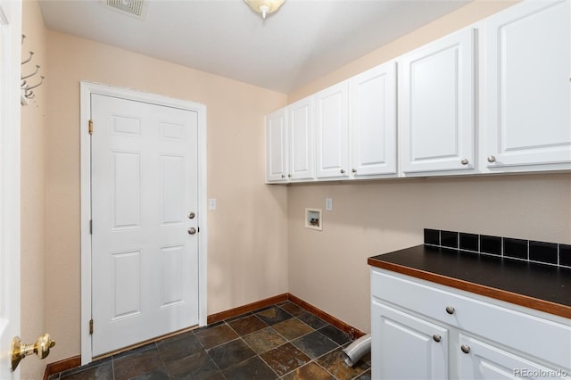 washroom featuring cabinet space, visible vents, baseboards, hookup for a washing machine, and stone finish flooring