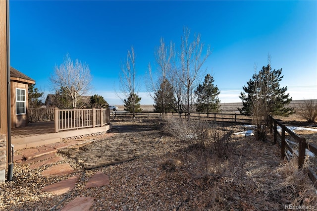 view of yard with a rural view, fence, and a wooden deck