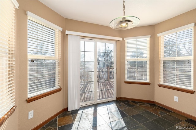 doorway with stone tile floors and baseboards