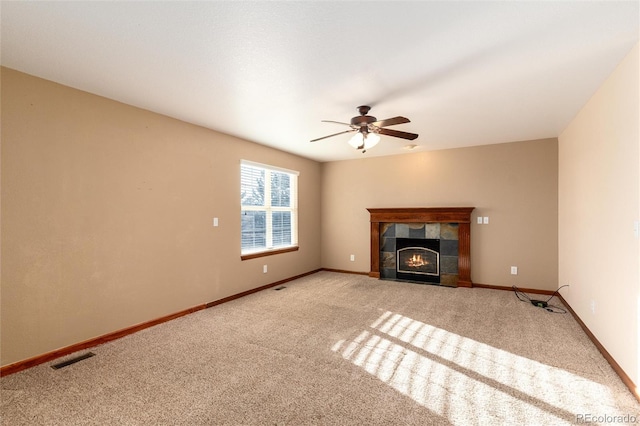 unfurnished living room featuring ceiling fan, a fireplace, visible vents, baseboards, and carpet