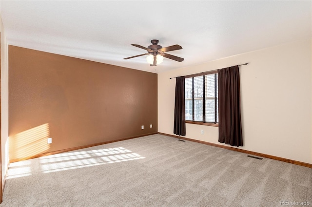 empty room with carpet floors, ceiling fan, visible vents, and baseboards