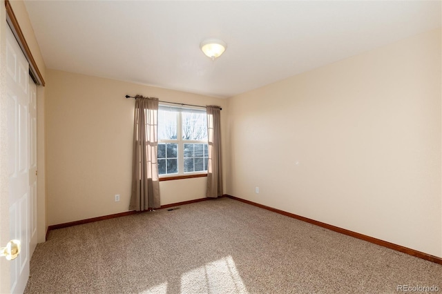 carpeted empty room featuring baseboards