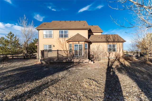 rear view of house featuring fence and a deck