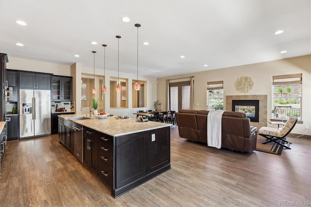 24322 E Mineral Dr, Aurora, CO 80016 - kitchen featuring stainless steel appliances, dark wood-style flooring, recessed lighting, an island with sink, and light stone countertops