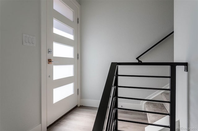 staircase featuring baseboards and wood finished floors