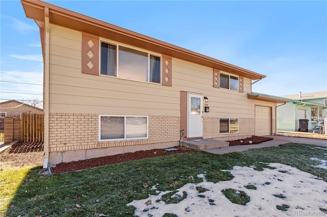 view of front facade with a front yard, a garage, and cooling unit