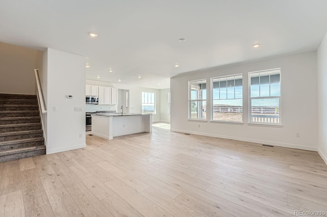 unfurnished living room featuring sink and light hardwood / wood-style floors