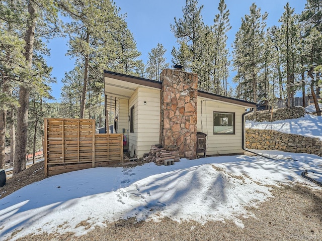 snow covered property with a chimney and fence