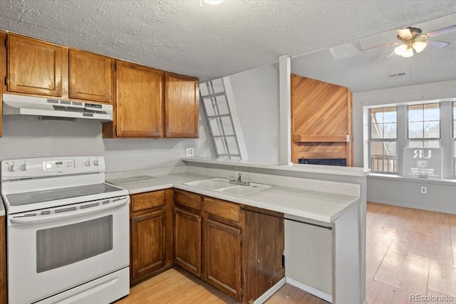 kitchen with electric stove, sink, ceiling fan, a textured ceiling, and kitchen peninsula