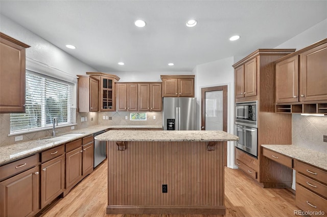16043 Bridle Ridge Dr, Monument, CO 80132 - kitchen with stainless steel appliances, a sink, a center island, light wood finished floors, and light stone countertops