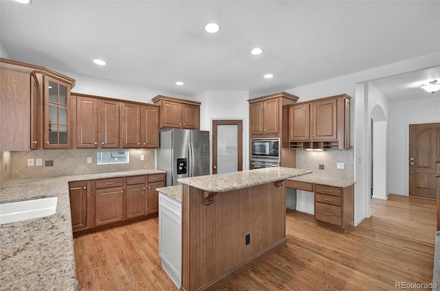 16043 Bridle Ridge Dr, Monument, CO 80132 - kitchen featuring appliances with stainless steel finishes, arched walkways, light wood-type flooring, brown cabinetry, and recessed lighting
