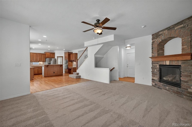 16043 Bridle Ridge Dr, Monument, CO 80132 - unfurnished living room featuring light carpet, ceiling fan, a fireplace, recessed lighting, and stairway