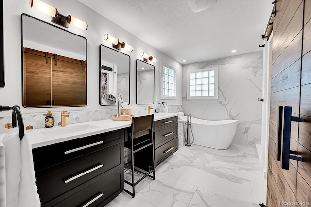 8427 S Parfet Ct, Littleton, CO 80127 - full bathroom featuring double vanity, marble finish flooring, a freestanding tub, and a textured ceiling