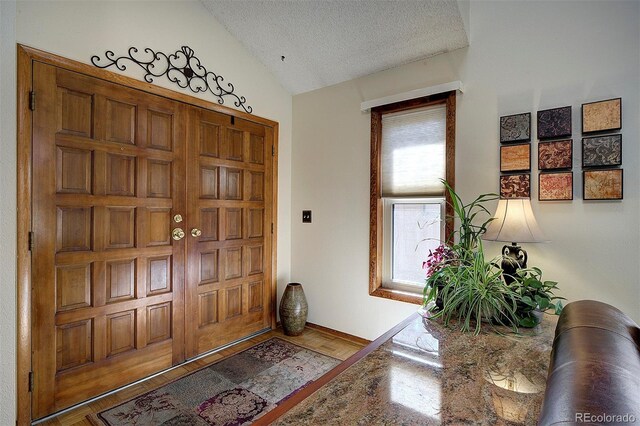 foyer entrance with vaulted ceiling and a textured ceiling