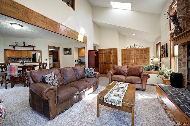 living area featuring a skylight, high vaulted ceiling, and light colored carpet