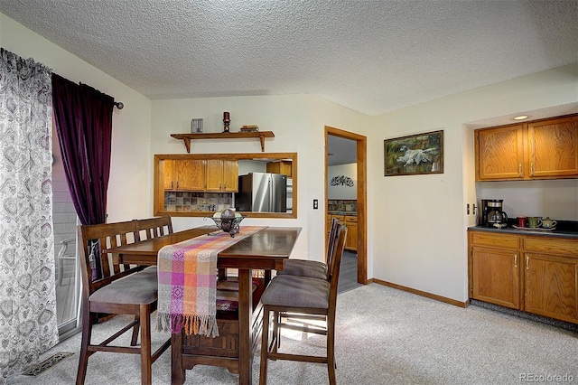 dining space featuring light carpet, a textured ceiling, visible vents, and baseboards