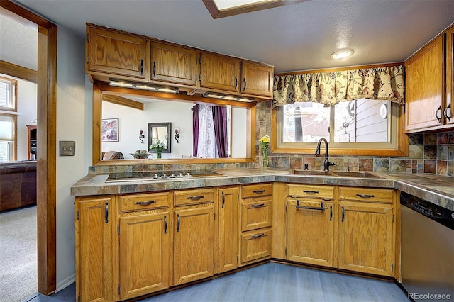 kitchen with black electric stovetop, backsplash, brown cabinetry, a sink, and dishwasher