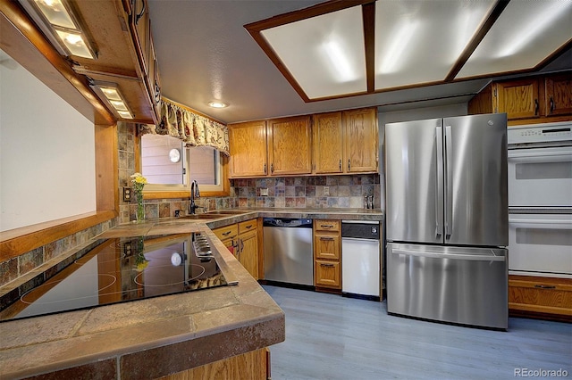 kitchen featuring brown cabinets, light wood-type flooring, stainless steel appliances, and backsplash