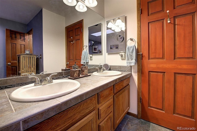 full bath featuring double vanity, tile patterned flooring, a sink, and an inviting chandelier