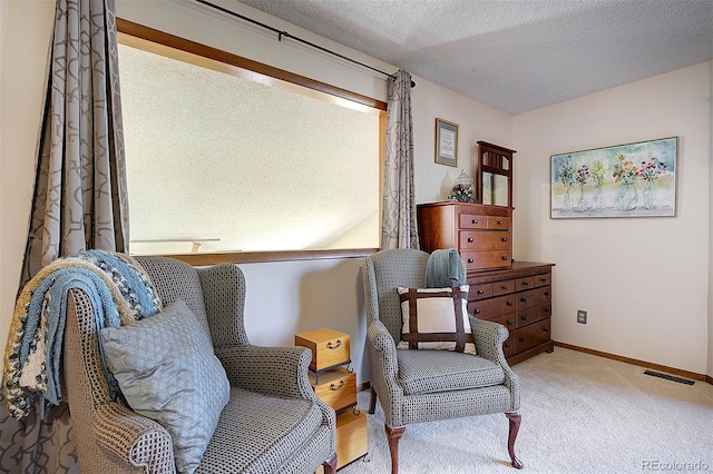 living area featuring light carpet, visible vents, a textured ceiling, and baseboards