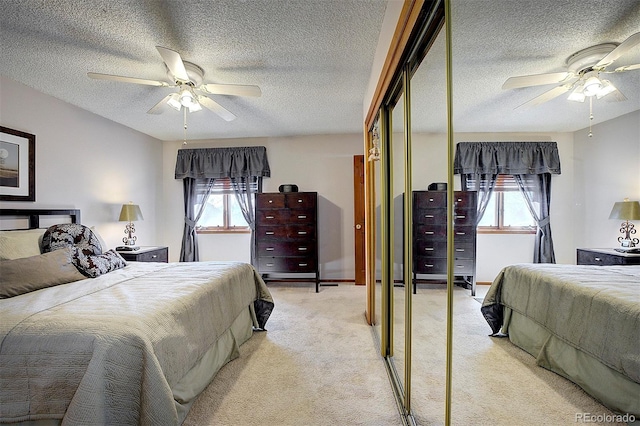 bedroom featuring light carpet, ceiling fan, and a textured ceiling