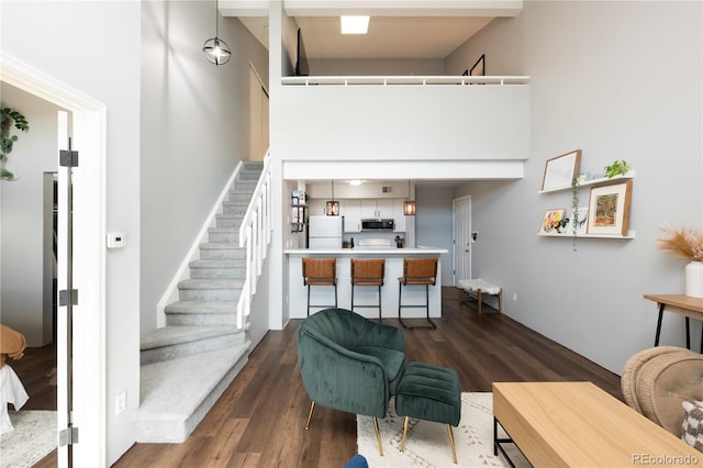 living room with dark wood-style flooring, a high ceiling, and stairway