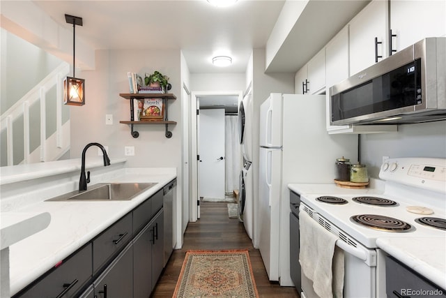 kitchen with stainless steel appliances, dark wood-style flooring, a sink, stacked washer / drying machine, and light countertops