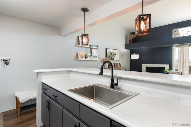 kitchen featuring a fireplace, a sink, open floor plan, hanging light fixtures, and dark wood finished floors