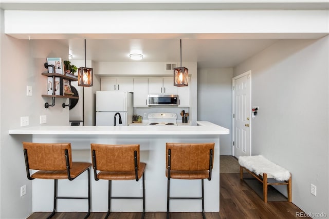 kitchen with visible vents, stove, stainless steel microwave, a breakfast bar area, and freestanding refrigerator