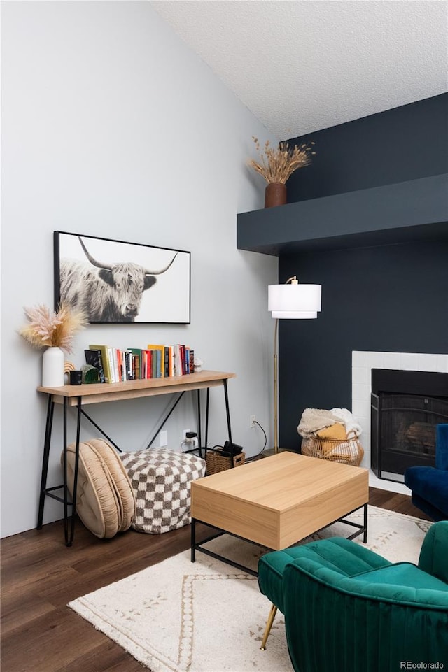 sitting room with a fireplace, a textured ceiling, and wood finished floors