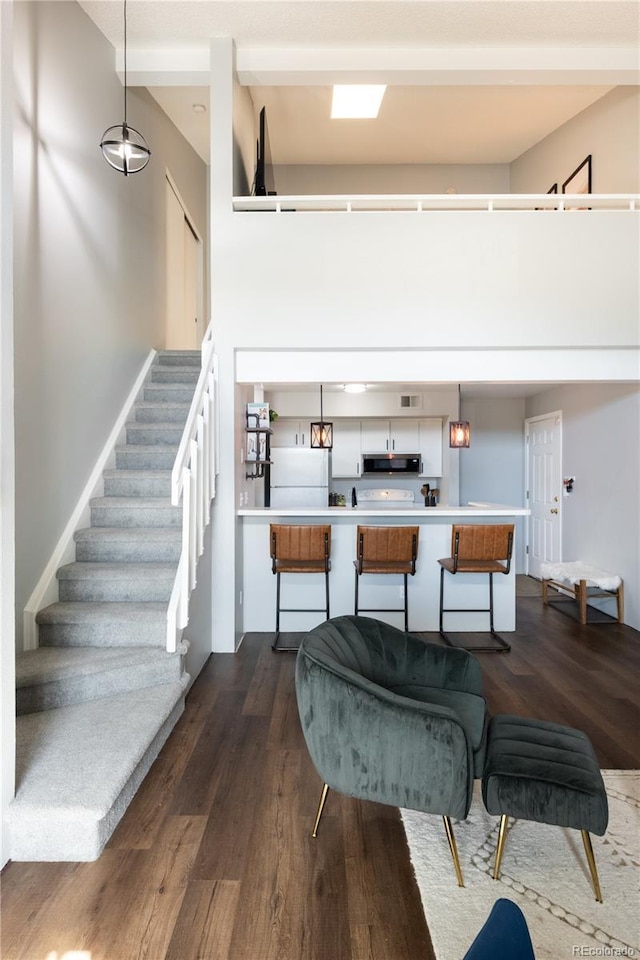 interior space with dark wood-type flooring, a high ceiling, light countertops, freestanding refrigerator, and stainless steel microwave