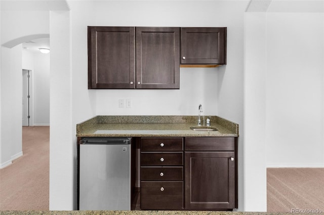 178 Coyote Willow, Colorado Springs, CO 80921 - kitchen with light carpet, a sink, refrigerator, dark brown cabinets, and arched walkways