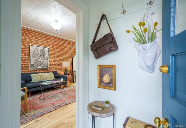 mudroom featuring wood finished floors and brick wall