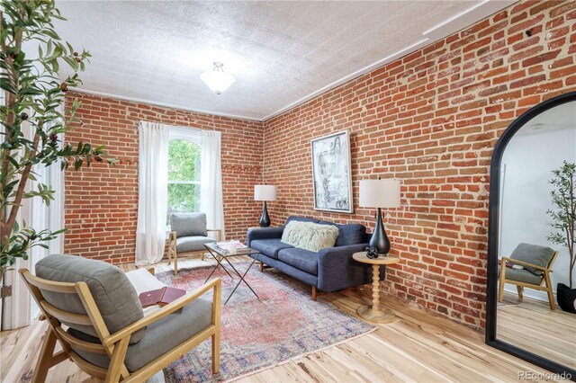 living room featuring wood finished floors, a textured ceiling, brick wall, and arched walkways