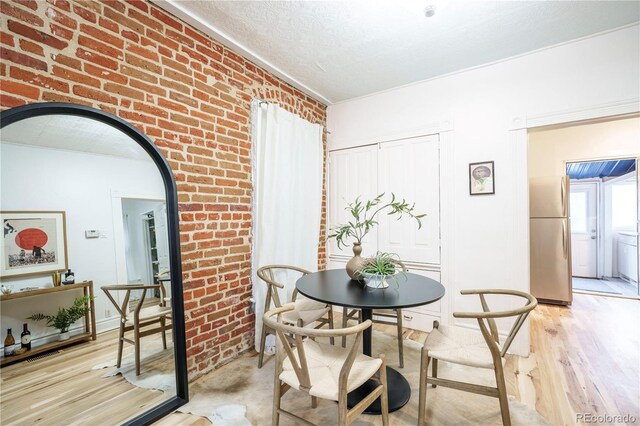 dining space featuring brick wall, light wood finished floors, and arched walkways