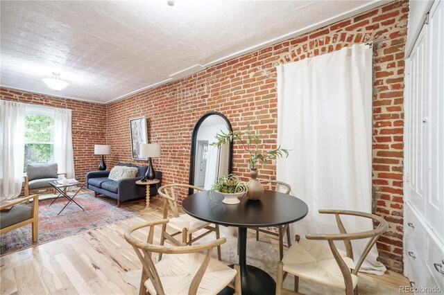 dining space with brick wall, a textured ceiling, wood finished floors, and arched walkways
