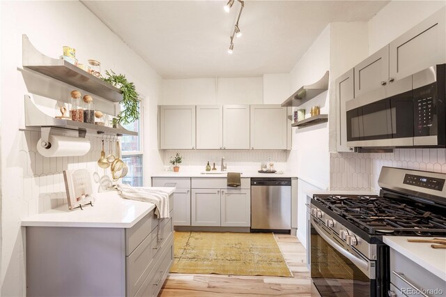 kitchen featuring open shelves, stainless steel appliances, gray cabinets, and decorative backsplash