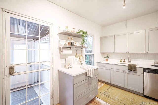 kitchen featuring dishwasher, gray cabinets, light countertops, and a sink