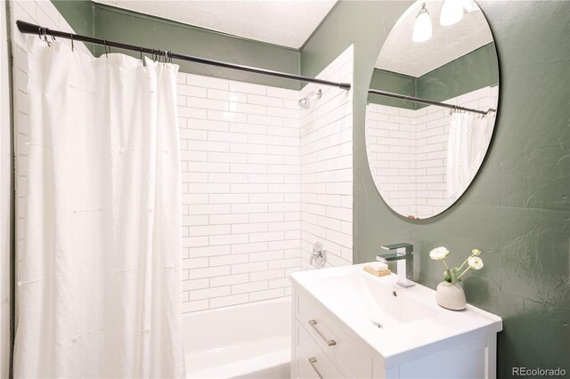 full bath featuring vanity, shower / bath combination with curtain, and a textured wall