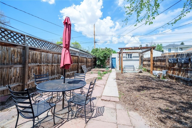 view of patio / terrace featuring a fenced backyard, a shed, outdoor dining space, and an outdoor structure
