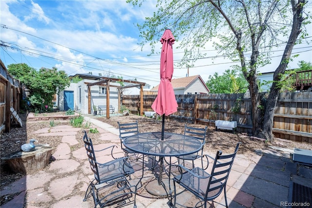 view of patio / terrace featuring a fenced backyard, outdoor dining space, and an outdoor structure