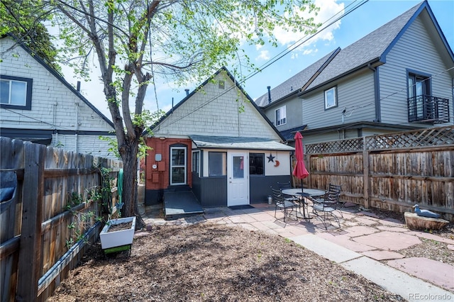 back of property featuring a patio, a fenced backyard, roof with shingles, and a garden