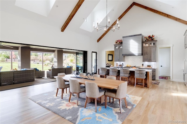 dining space with an inviting chandelier, light hardwood / wood-style flooring, beamed ceiling, and high vaulted ceiling