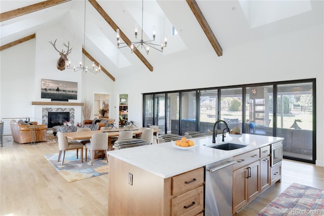 kitchen with a fireplace, sink, a chandelier, high vaulted ceiling, and a center island with sink