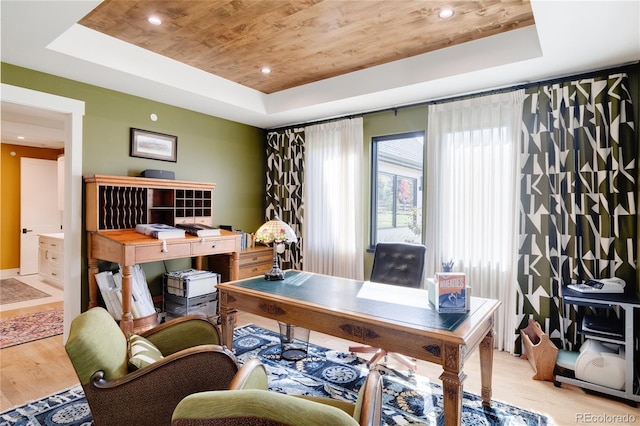 home office featuring a raised ceiling, light hardwood / wood-style flooring, and wooden ceiling